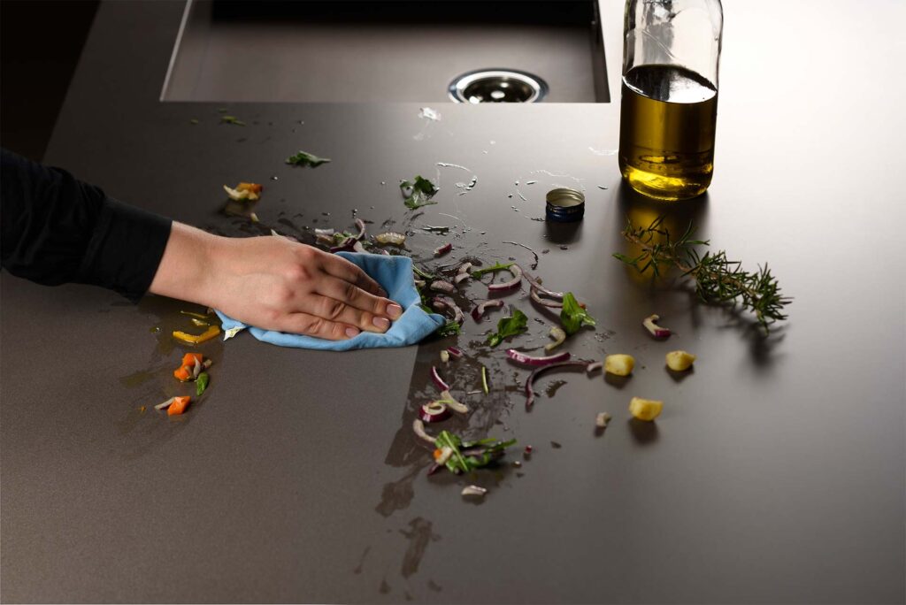 A person easily wiping a Lapitec sintered stone countertop in a Sarasota kitchen, demonstrating its non-porous, stain-proof surface—far superior to quartz.