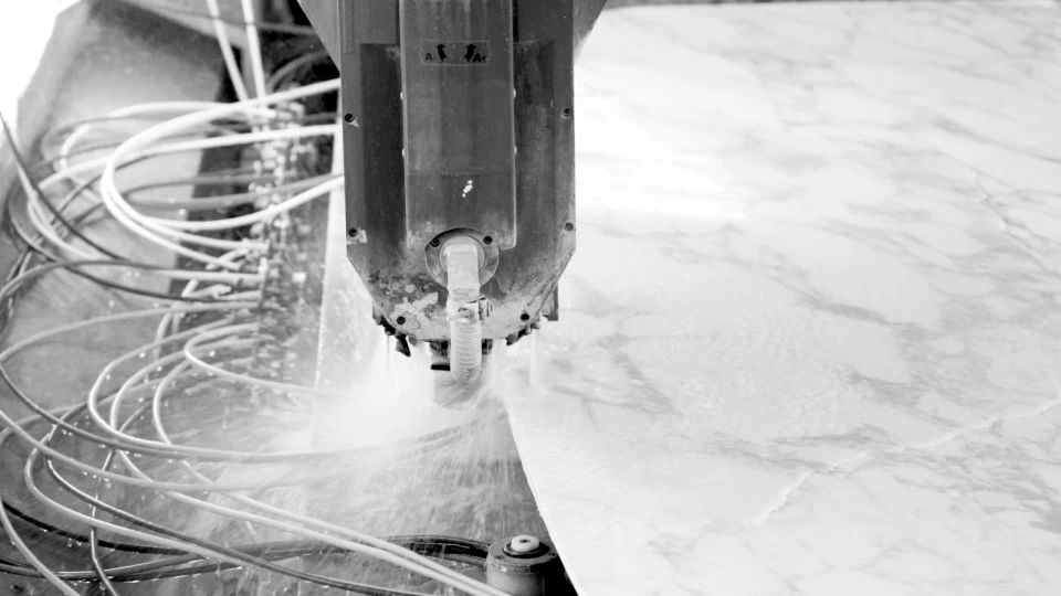 A high-powered water jet precisely cuts a large porcelain slab, showcasing the specialized equipment required for dekton fabrication.