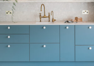 Terrazzo look Retrostone on a kitchen countertop and backsplash, harmonizing with blue cabinet colors.