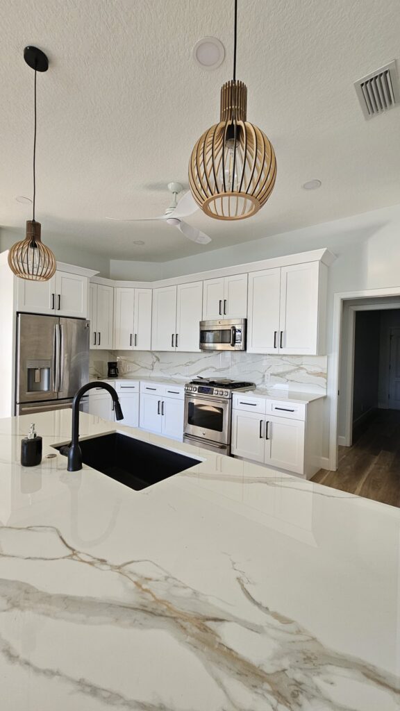 A luxury kitchen island showcasing the bookmatched veining of an Infinity Calacatta Oro polished 2cm porcelain slab.